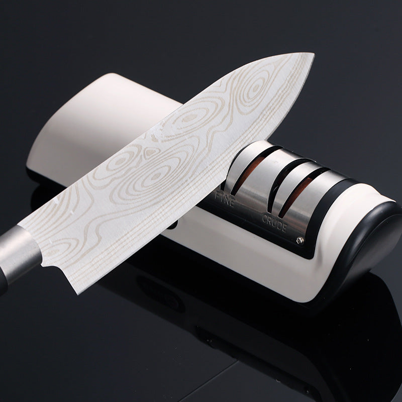 Peilis su medžio raštu, sidabriniu ašmeniu ir baltu galandimo įrankiu.