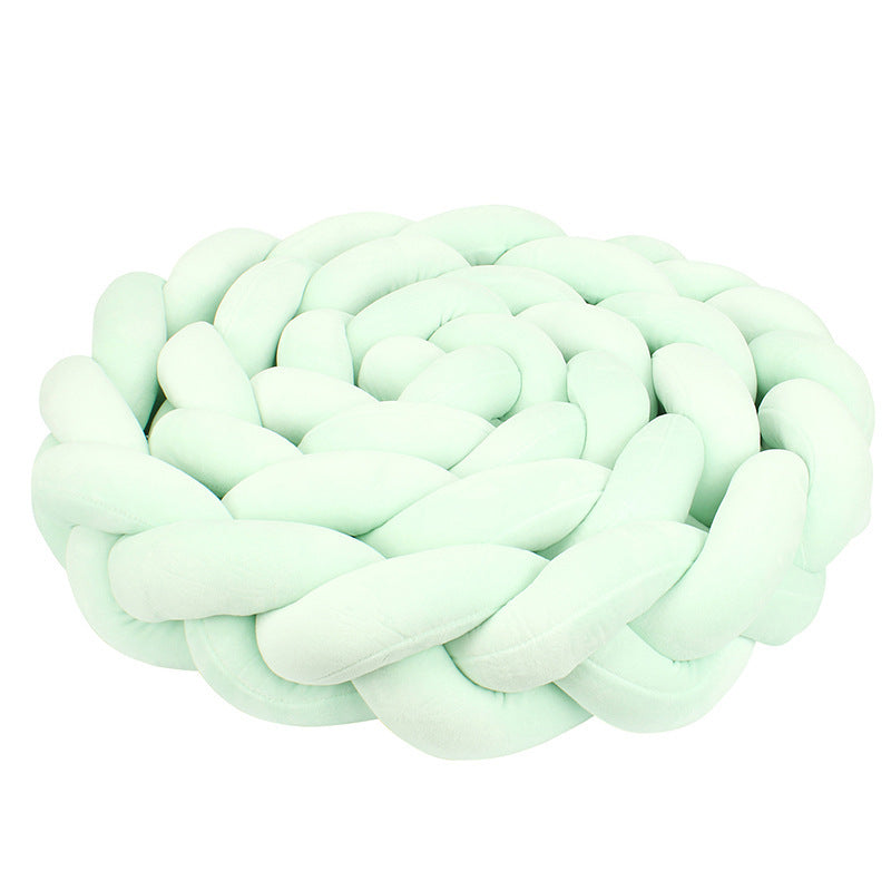 Minkštas, šviesiai žalias, pintas kilimėlis su apvalia forma.