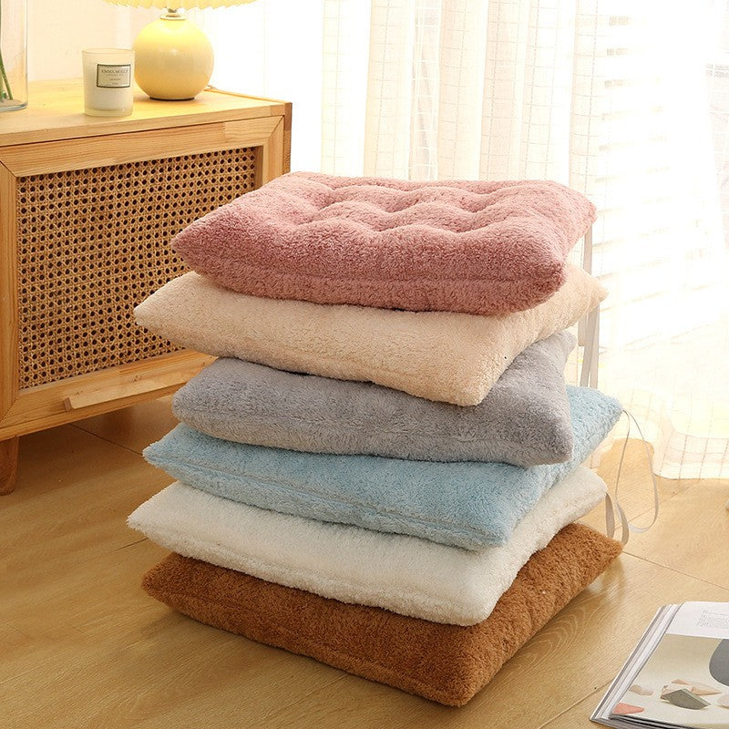 Spalvoti, minkšti pagalvėlės, su švelnia tekstūra, sukrautos ant medinio paviršiaus.