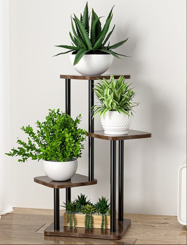 Medinis gėlių stovas su juodais metaliniais stulpeliais, ant jo žali augalai.