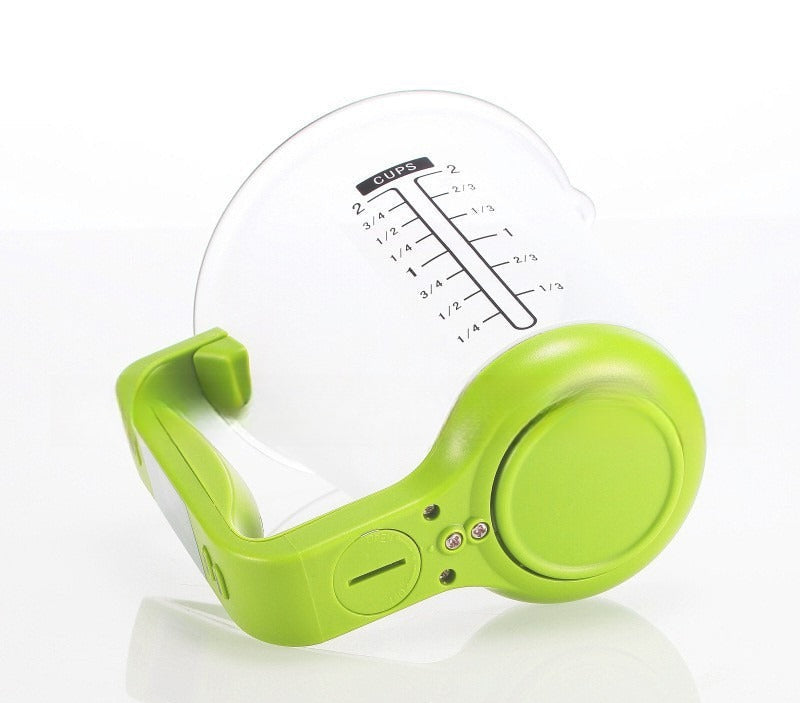 Žalias matavimo puodelis su skaidriu stiklu ir aiškiais žymėjimais.